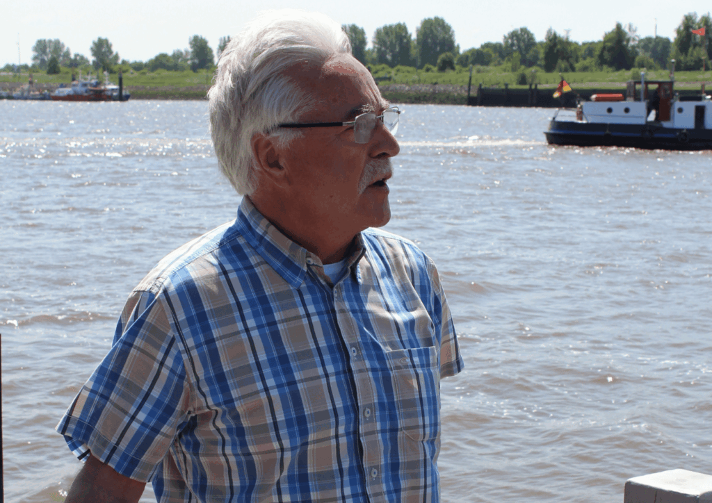 Portraitfoto von Dieter Stratmann, im hintergrund ein Wendebecken, ein Schiffanlager und dein Stück Schiff.
